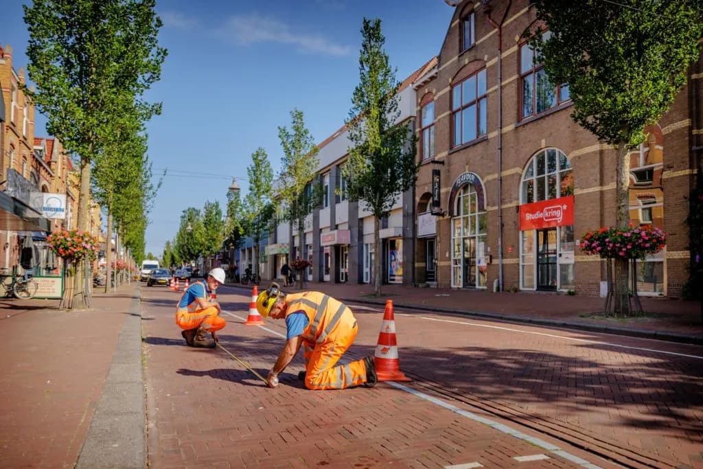 Twee SPOTTEN-monteurs installeren een sensor in het wegdek van een winkelstraat